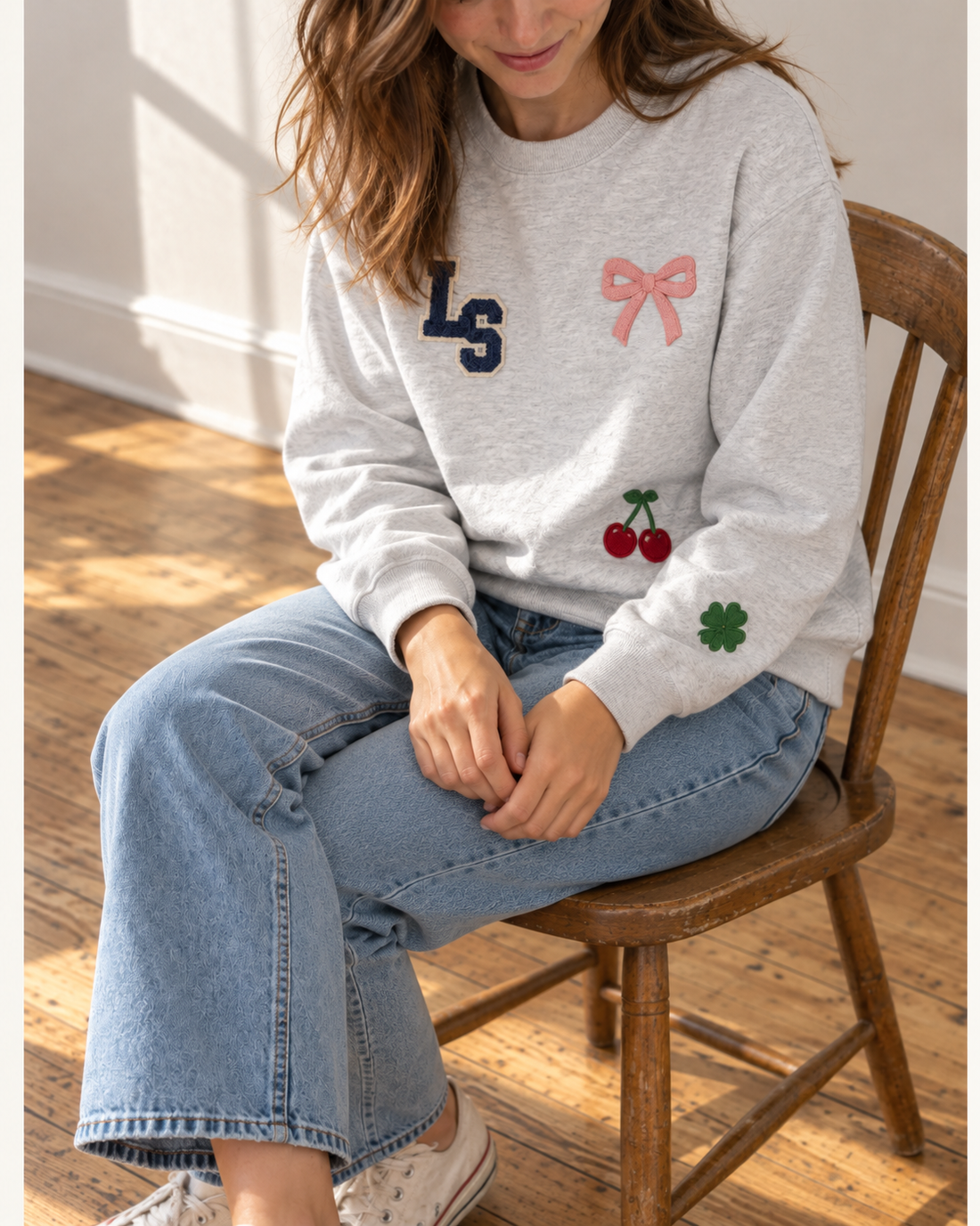 Woman wearing a heather grey patch crewneck with monogram, bow, cherries and clover patches, a maid of honor gift