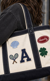 Woman carrying The Everyday Tote with seashell, tennis rackets, A letter, Howdy and clover patches